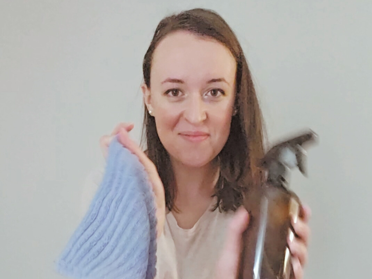 woman holding a cleaning rag and a bottle of cleaner