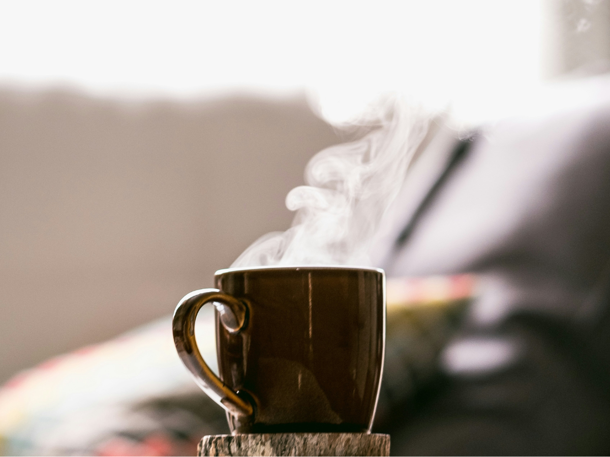 a steaming cup of coffee in a brown mug