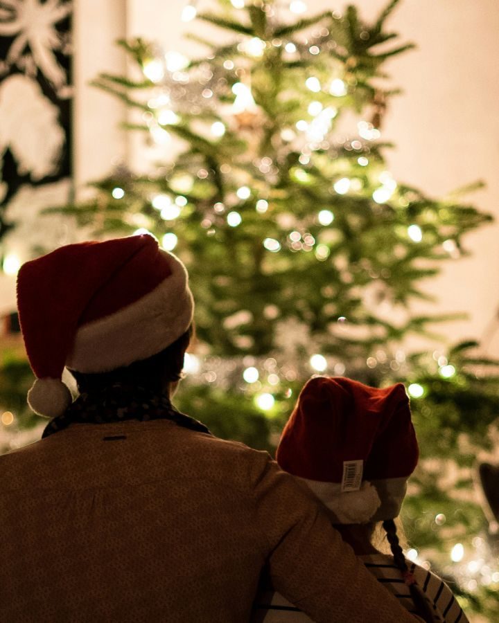 family looking at Christmas tree with Christmas hats on