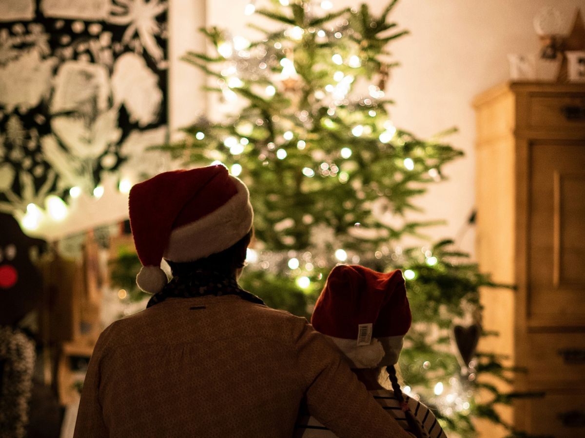 family looking at Christmas tree with Christmas hats on